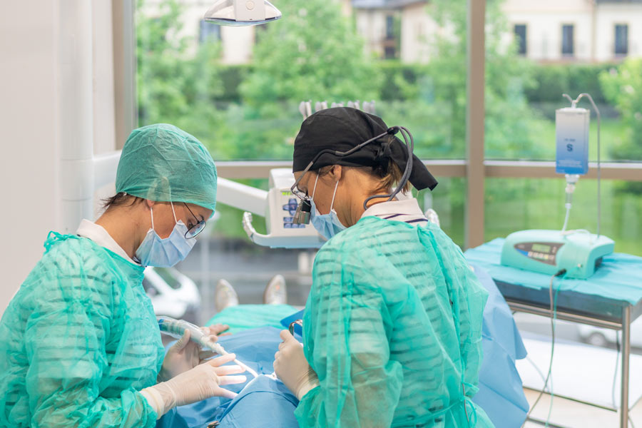 Odontóloga y auxiliar realizando una cirugía periodontal